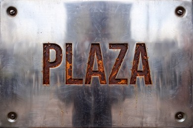 Metal plate with engraved rusted lettering.